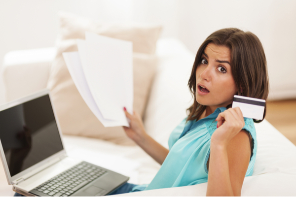 distressed woman reviewing bills and holding up credit card