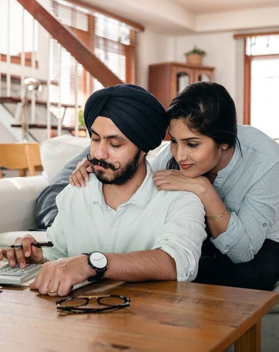 Focused young Indian couple working at home using calculator